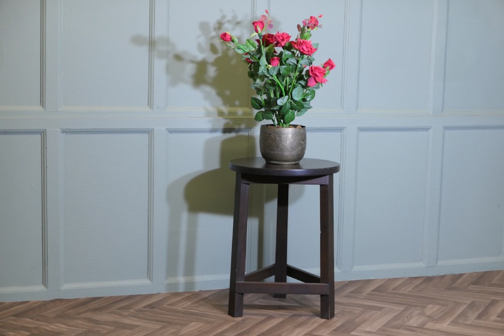 A dark-stained English oak cricket table featuring a circular top supported by three straight legs joined by a lower triangular stretcher. View V