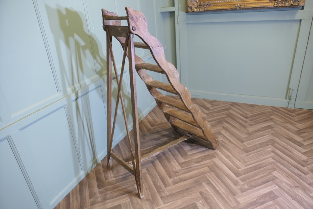 A nineteenth-century folding pine step ladder featuring scalloped wooden side supports and aged timber treads. View V