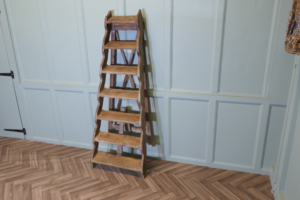A nineteenth-century folding pine step ladder featuring scalloped wooden side supports and aged timber treads. View VI