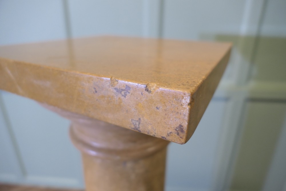 A tall honey-coloured marble column pedestal with a square top platform, cylindrical turned shaft, and square plinth base. View VI
