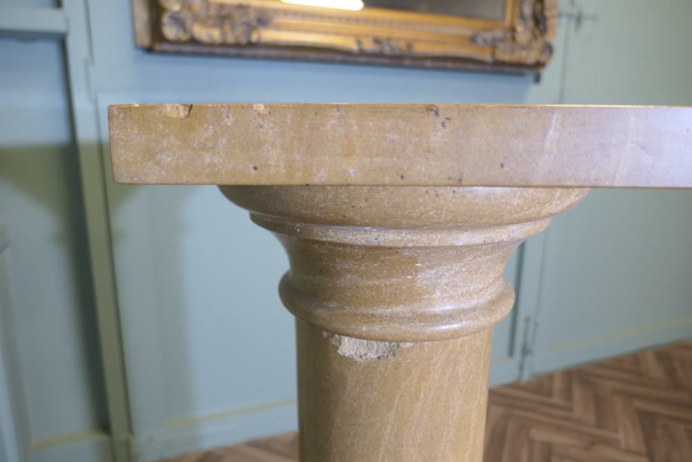 A tall honey-coloured marble column pedestal with a square top platform, cylindrical turned shaft, and square plinth base. View VII