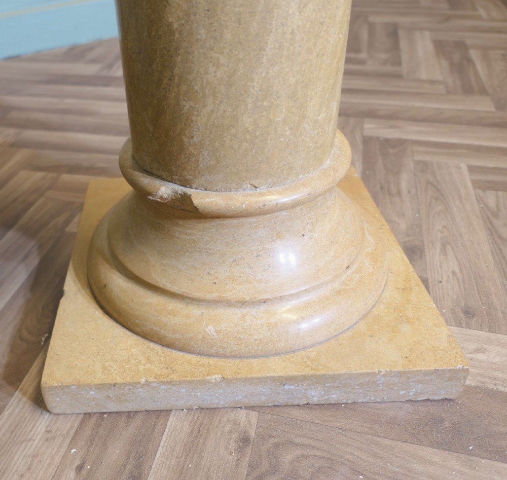 A tall honey-coloured marble column pedestal with a square top platform, cylindrical turned shaft, and square plinth base. View VIII