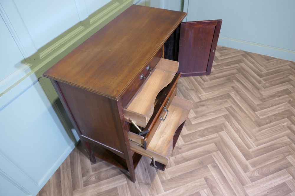 An Edwardian mahogany music cabinet featuring five drop-front drawers on the left, a single cupboard door on the right, brass drop handles, and an open lower shelf. View VI