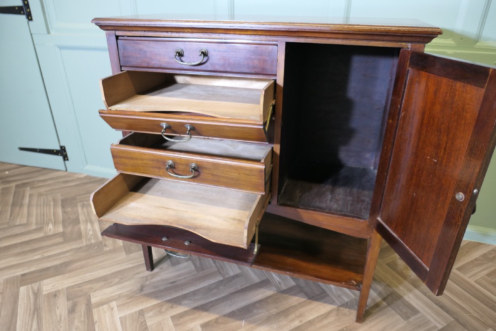 An Edwardian mahogany music cabinet featuring five drop-front drawers on the left, a single cupboard door on the right, brass drop handles, and an open lower shelf. View II