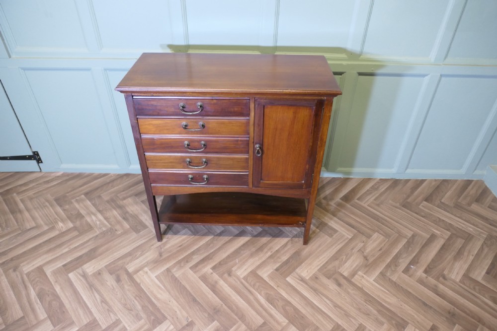 An Edwardian mahogany music cabinet featuring five drop-front drawers on the left, a single cupboard door on the right, brass drop handles, and an open lower shelf. View III