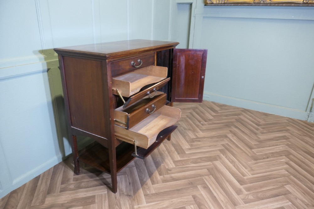 An Edwardian mahogany music cabinet featuring five drop-front drawers on the left, a single cupboard door on the right, brass drop handles, and an open lower shelf. View VII