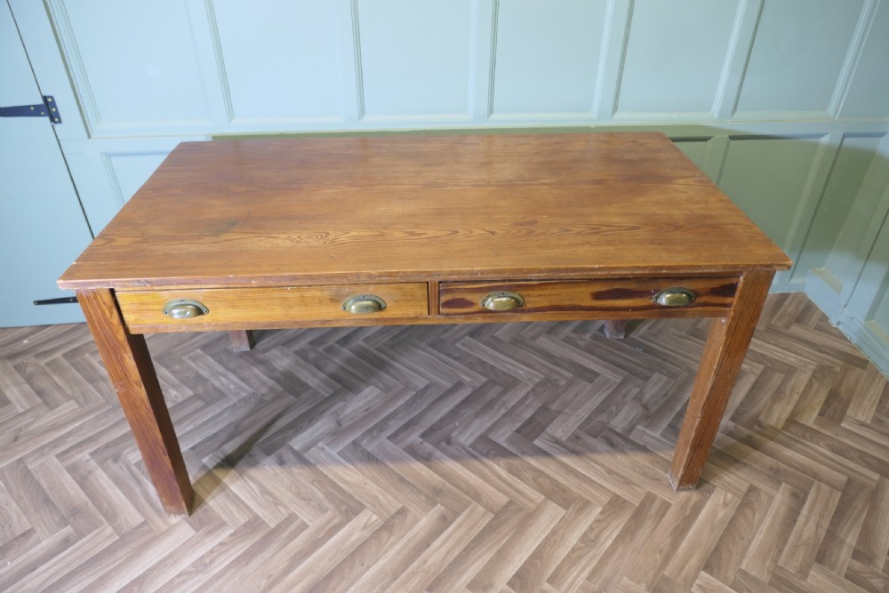 A rectangular antique pine writing table featuring two front drawers fitted with brass cup handles and supported by four straight square legs. View III