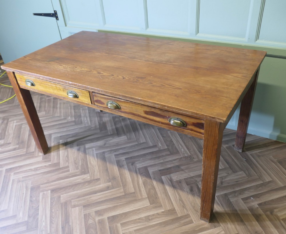 A rectangular antique pine writing table featuring two front drawers fitted with brass cup handles and supported by four straight square legs. View V