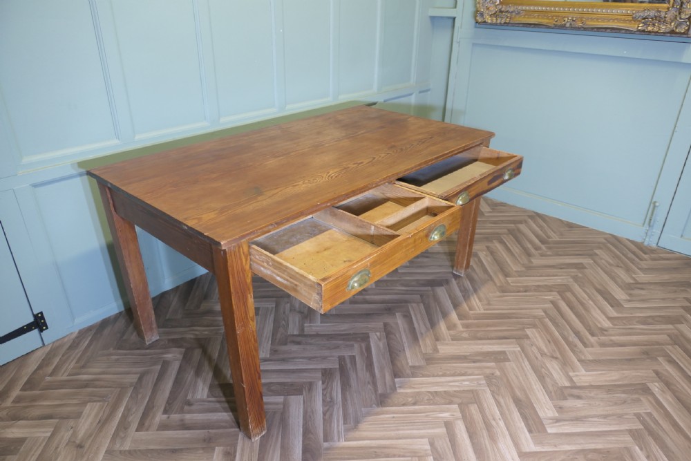 A rectangular antique pine writing table featuring two front drawers fitted with brass cup handles and supported by four straight square legs. View VI