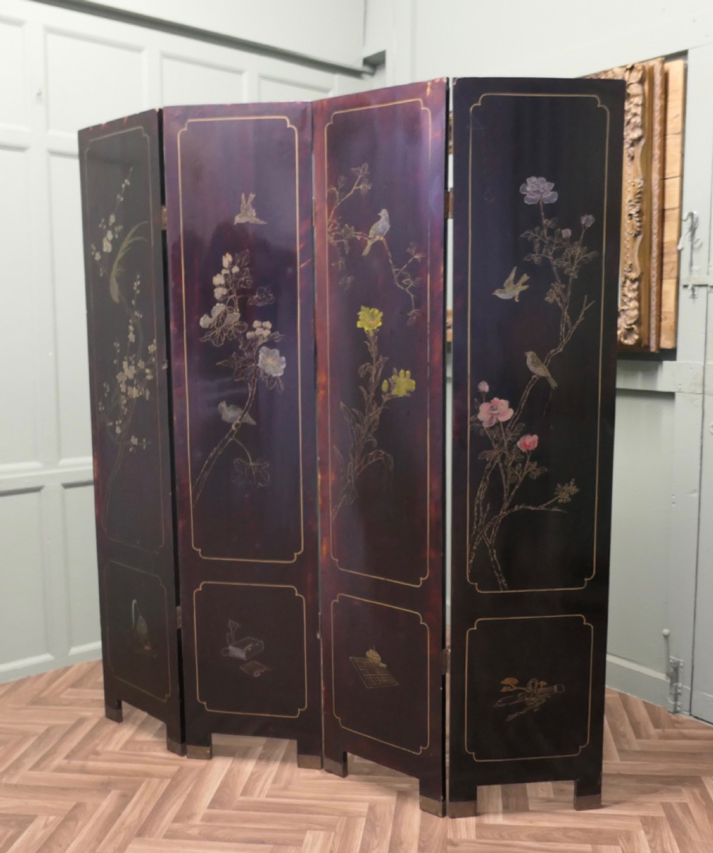A four-panel black lacquer folding screen decorated with gilt borders and inlaid polychrome relief figures depicting Japanese figures and garden scenery. View VI
