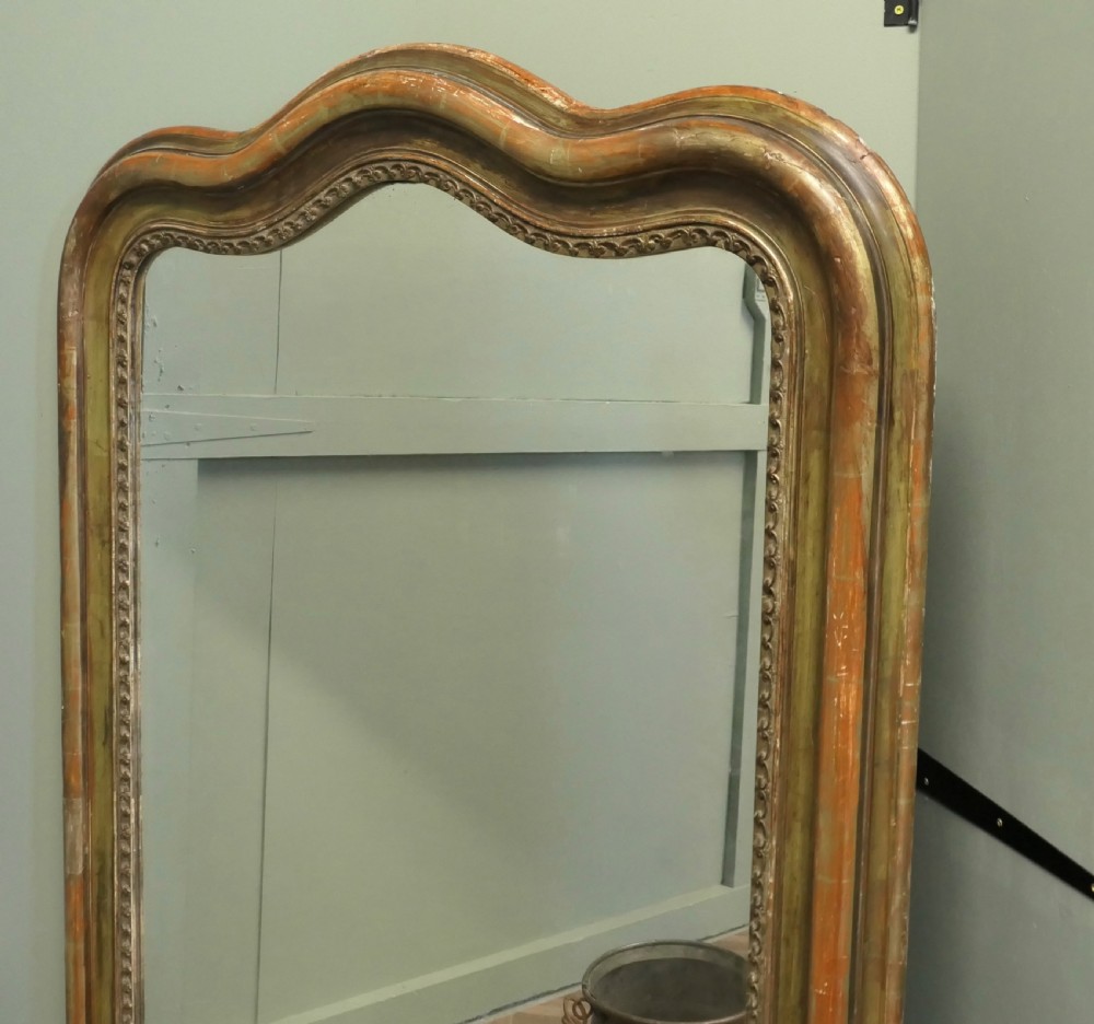 A tall 19th-century French Louis Philippe wall mirror featuring a rounded upper frame with worn antique gold gilding and a beaded inner border. View V