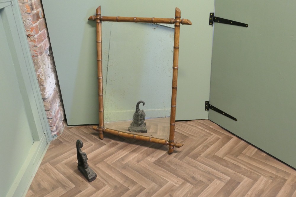 A rectangular French wall mirror featuring a natural bamboo frame with crossed corner joints.
