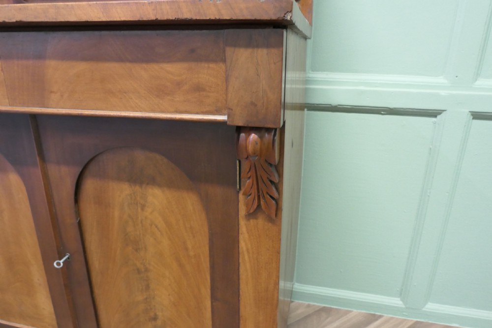 A Victorian mahogany chiffonier featuring a pedimented backboard with a shelf, turned supports, twin arched panel doors, and bun feet. View VI