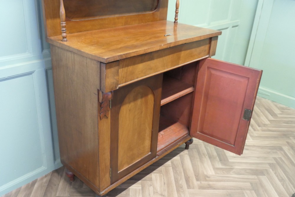 A Victorian mahogany chiffonier featuring a pedimented backboard with a shelf, turned supports, twin arched panel doors, and bun feet. View VII