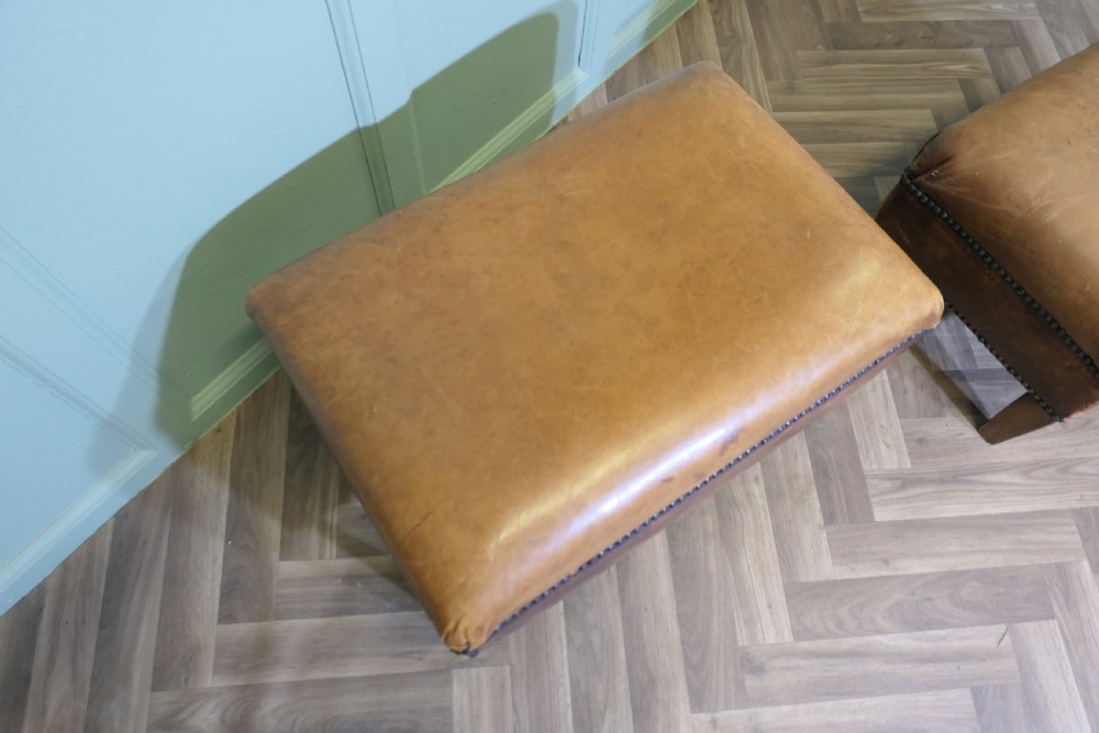 A pair of rectangular tan leather library footstools with close-studded trim detailing on tapered square wood legs. View III