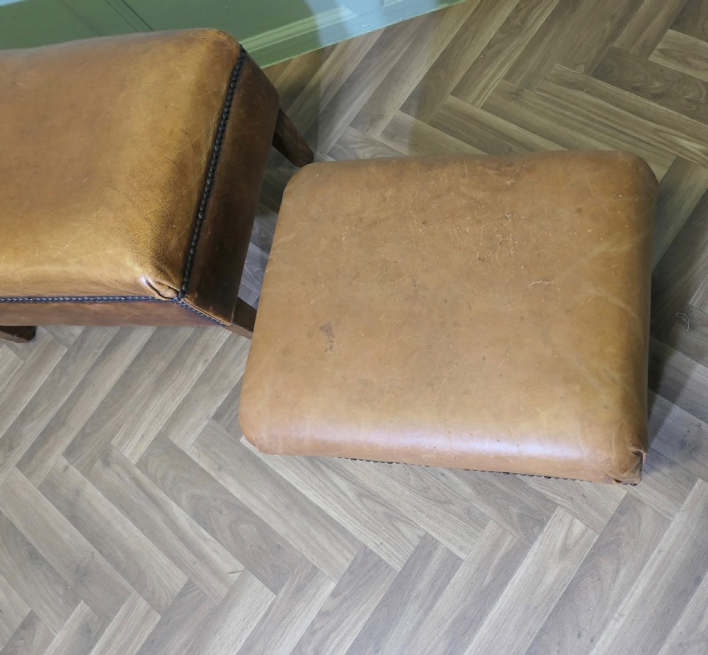 A pair of rectangular tan leather library footstools with close-studded trim detailing on tapered square wood legs. View VI