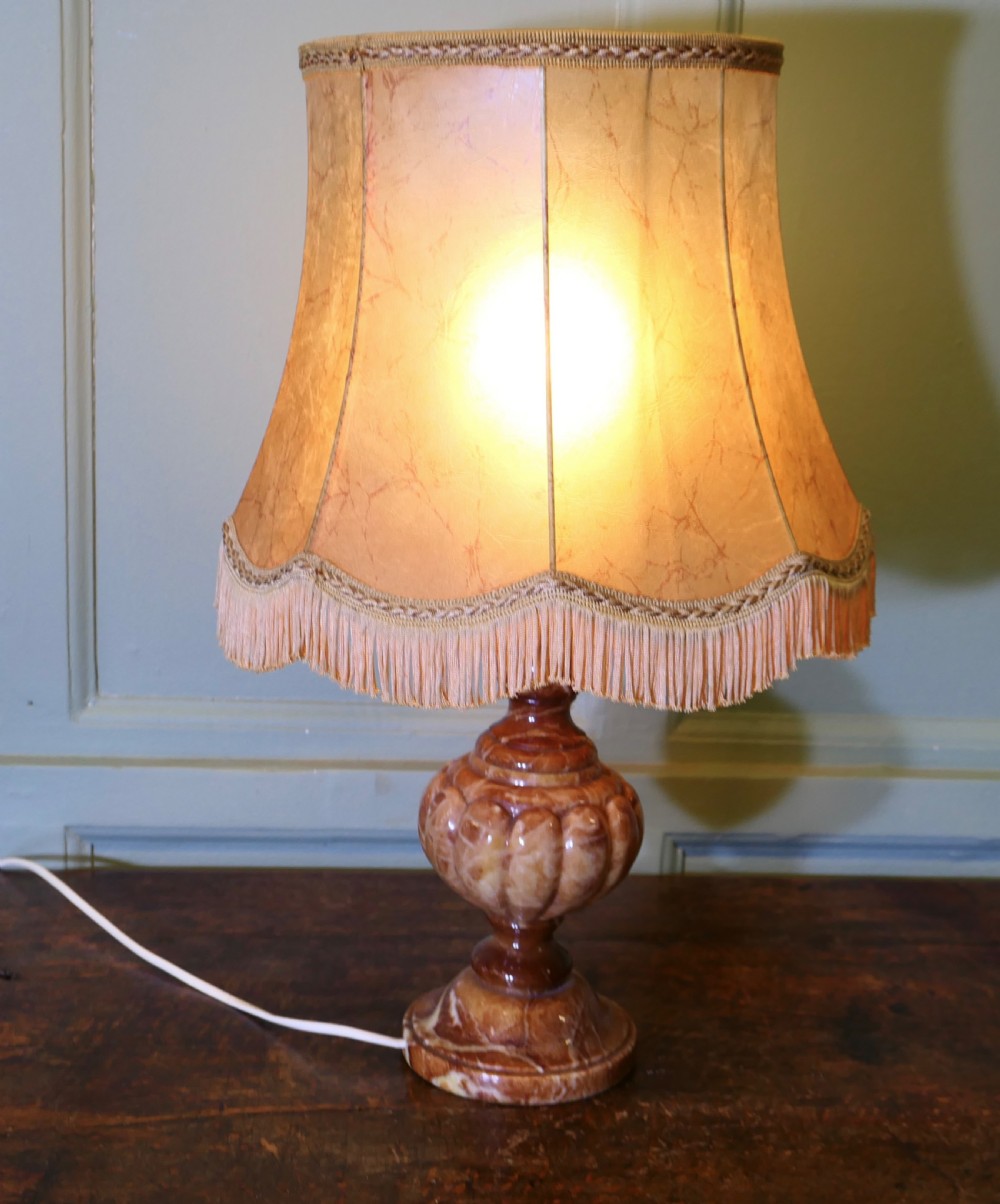An Art Deco table lamp featuring a carved variegated brown marble urn base and a flared beige lampshade with fringe details. View III