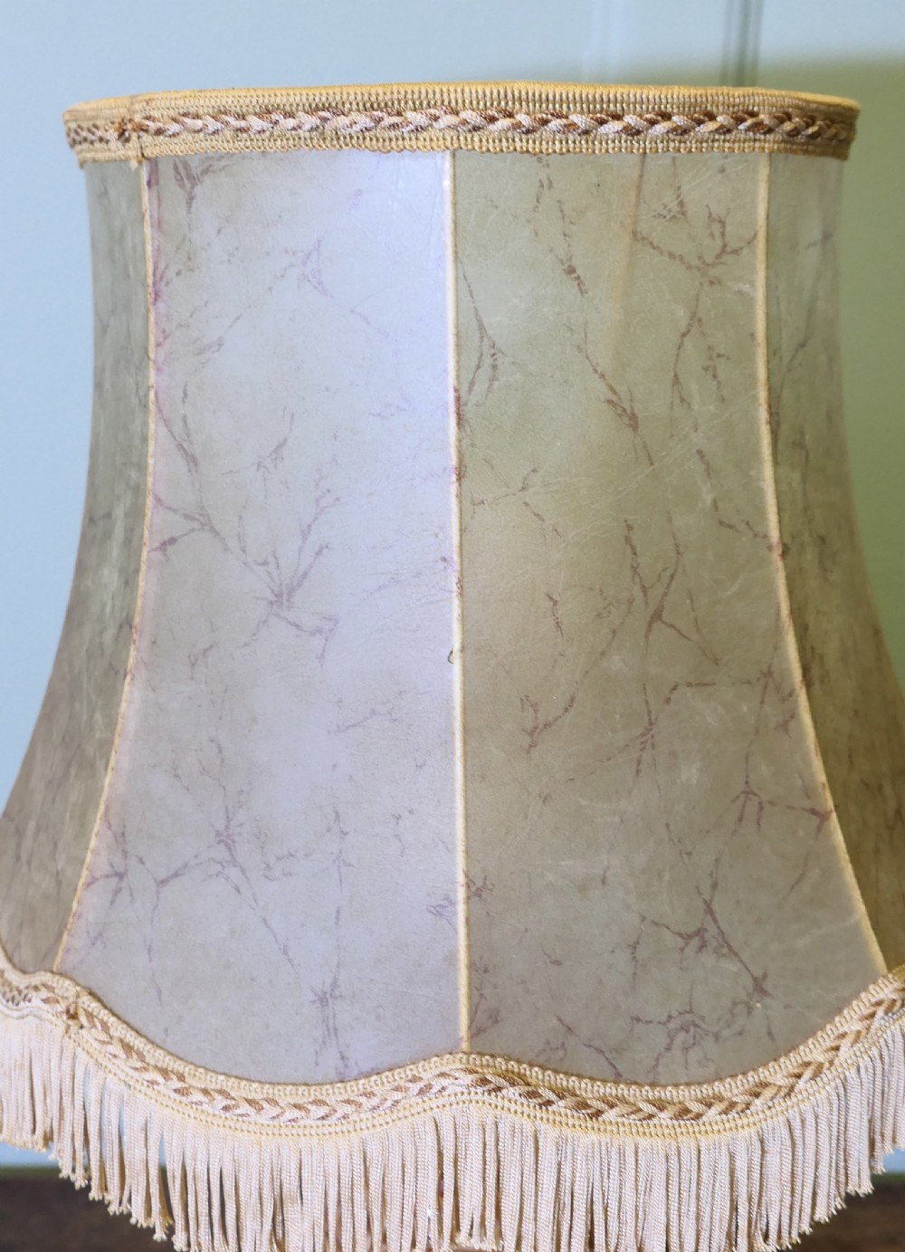 An Art Deco table lamp featuring a carved variegated brown marble urn base and a flared beige lampshade with fringe details. View VII