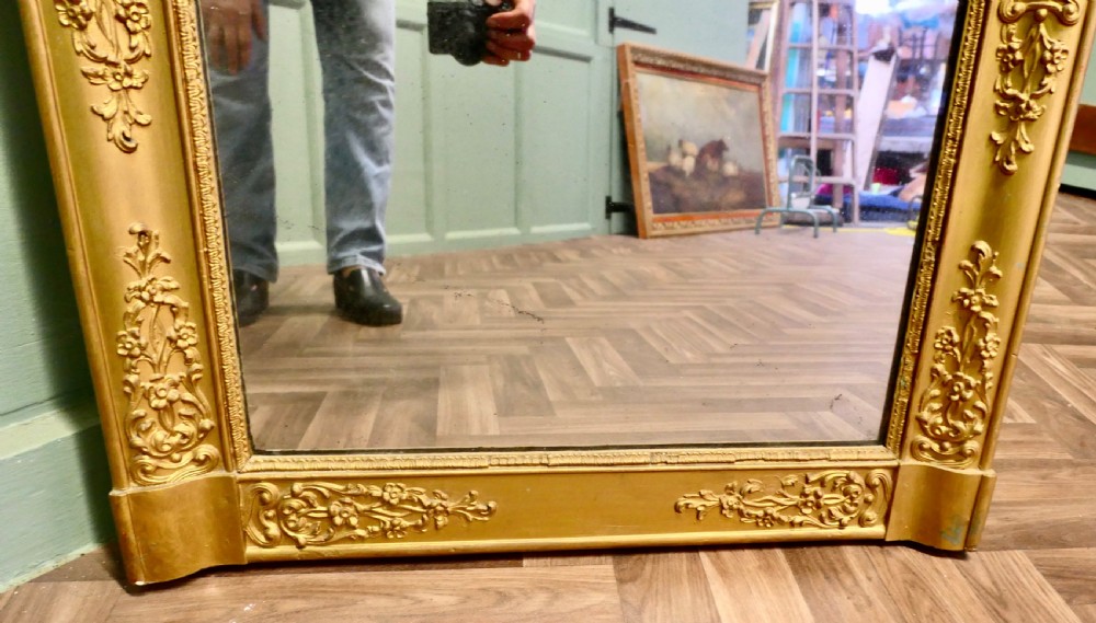 A rectangular French giltwood wall mirror featuring ornate floral moulding and foliate scrollwork along a gilded frame. View IV
