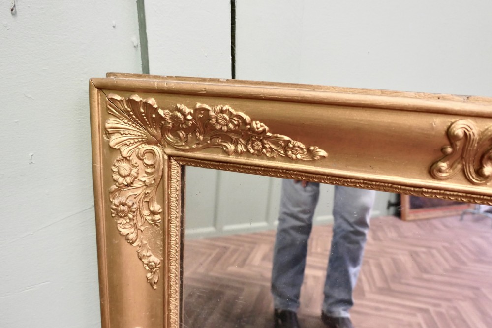 A rectangular French giltwood wall mirror featuring ornate floral moulding and foliate scrollwork along a gilded frame. View V