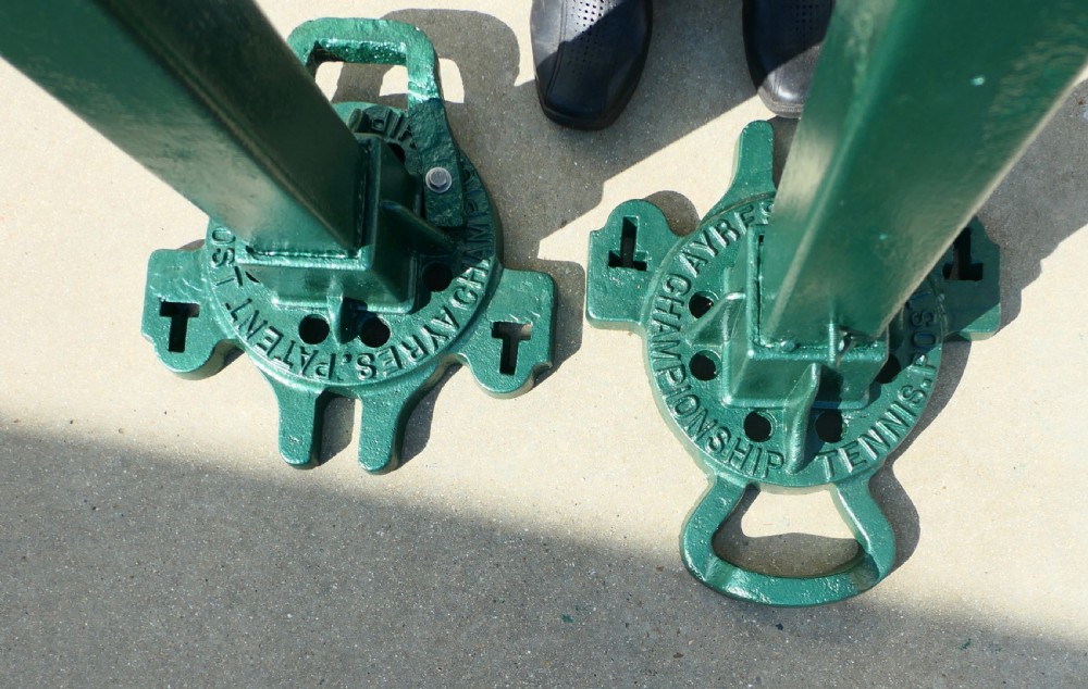 A pair of dark green painted Edwardian metal tennis court net posts featuring mechanical winder handles and heavy cast bases. View III