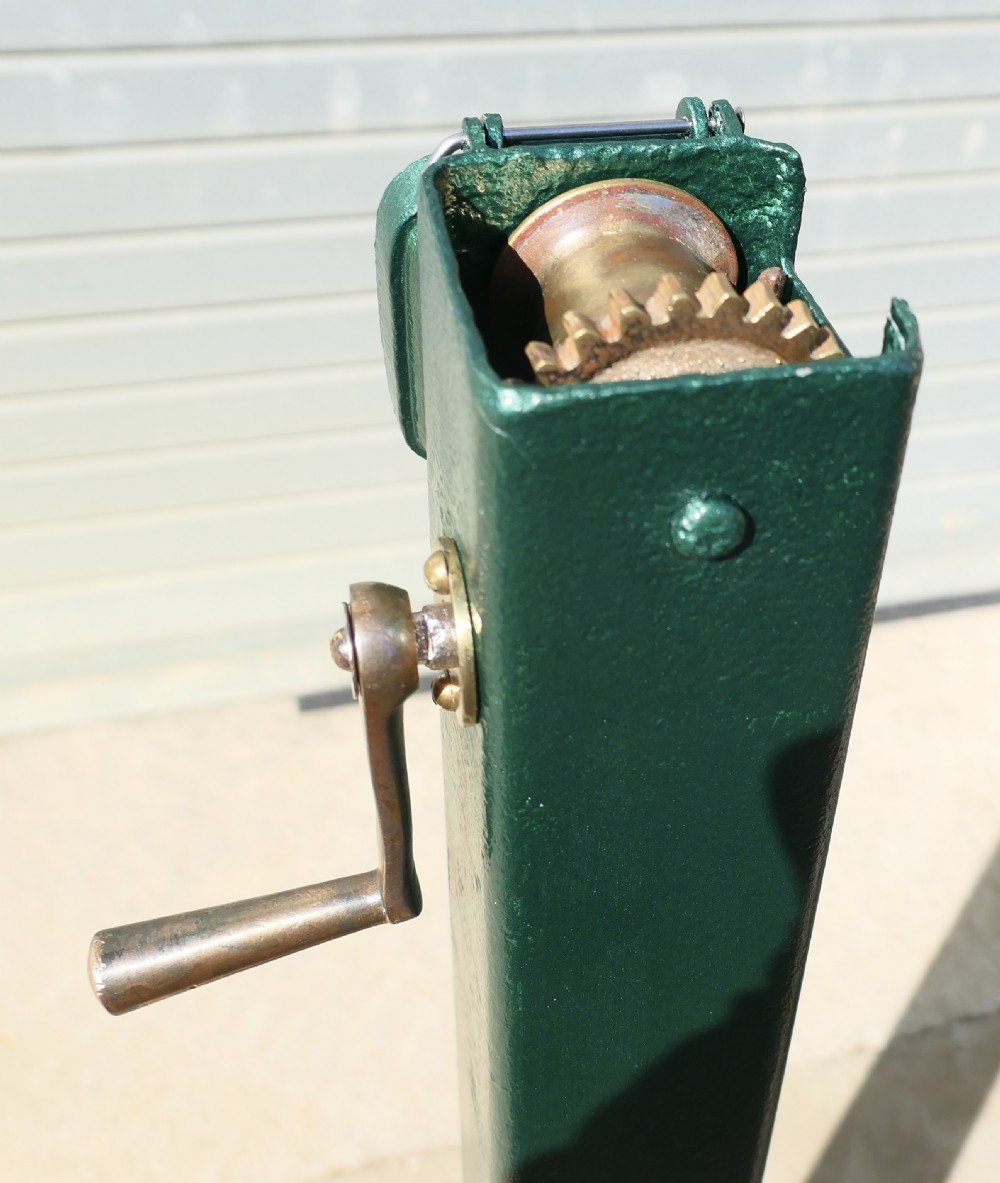 A pair of dark green painted Edwardian metal tennis court net posts featuring mechanical winder handles and heavy cast bases. View IV