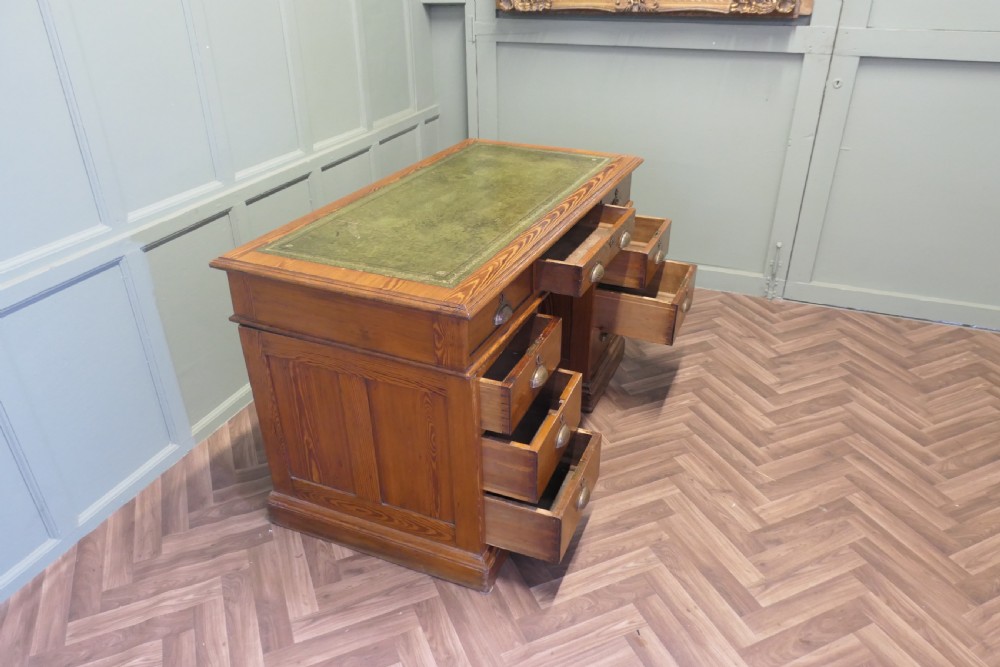 A late Victorian pitch pine pedestal desk featuring nine drawers with brass cup handles and panelled sides. View VII