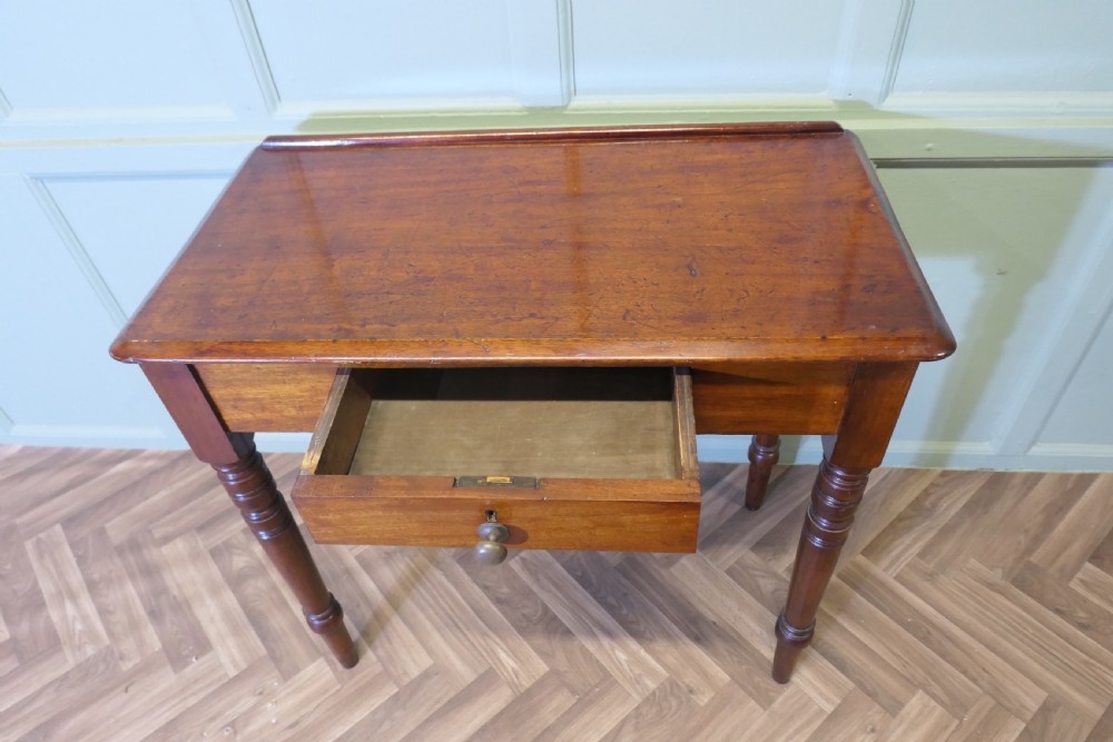 A small Victorian mahogany hall table featuring a rectangular top with a raised rear edge, turned legs, and an open side drawer displaying dovetail joinery. View VI