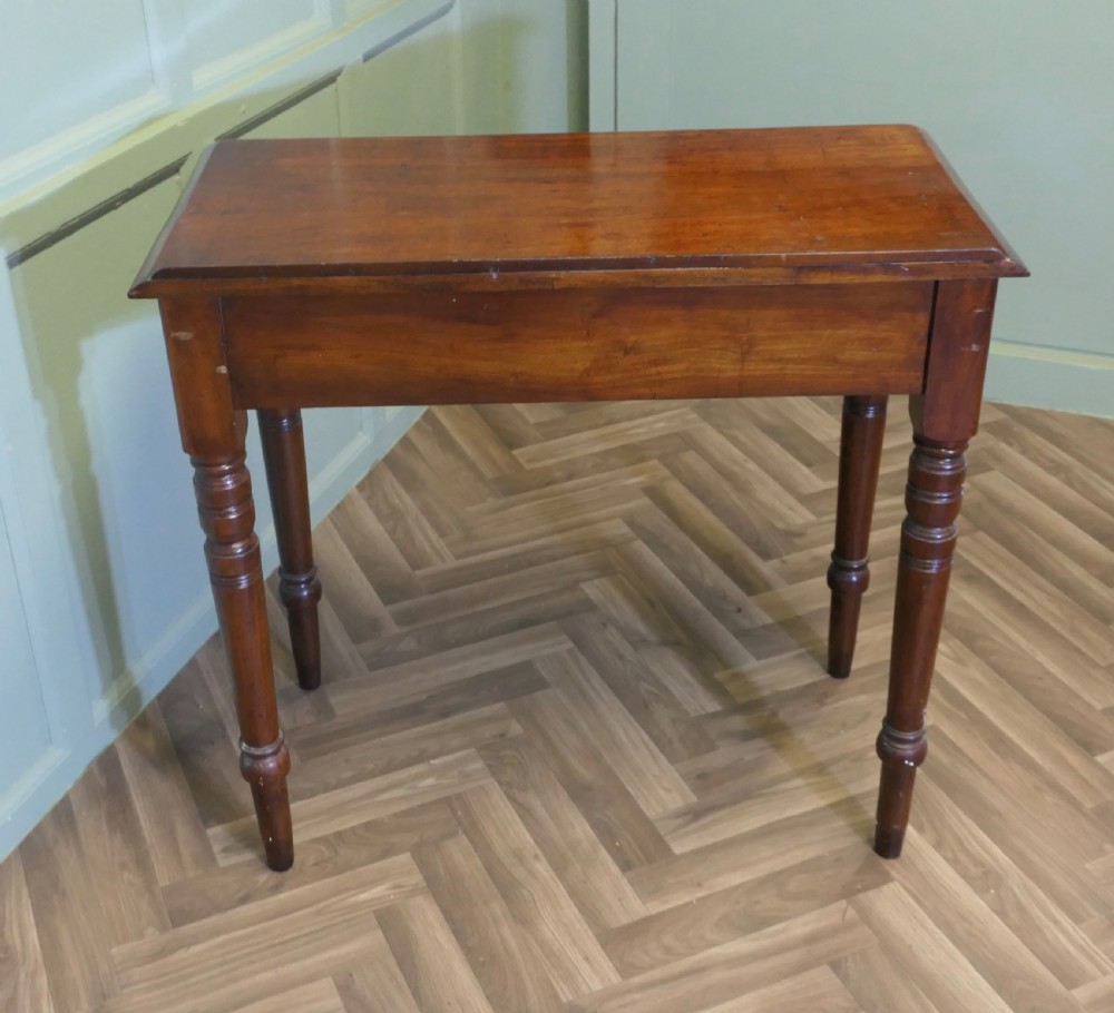 A small Victorian mahogany hall table featuring a rectangular top with a raised rear edge, turned legs, and an open side drawer displaying dovetail joinery. View VII