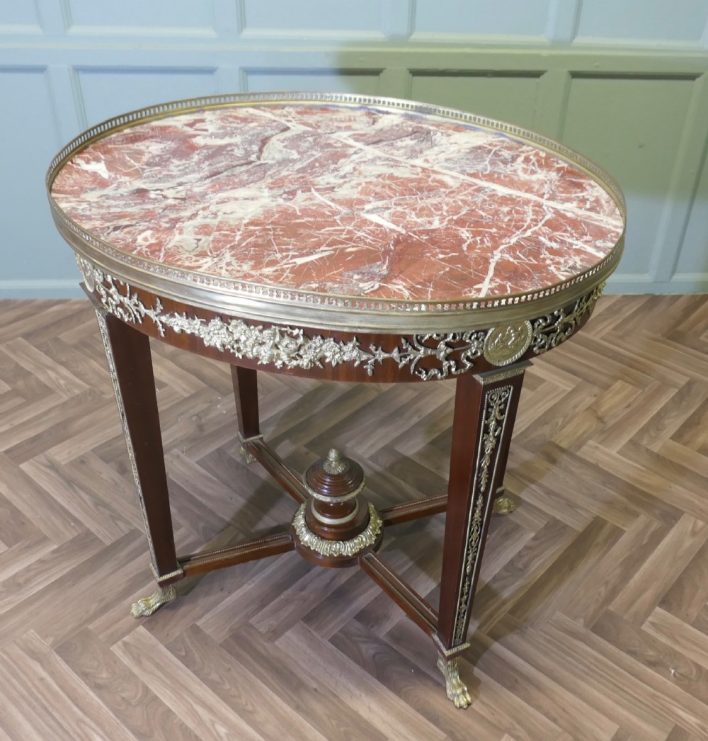 An oval French Empire style mahogany centre table featuring gilt bronze mounts, a brass gallery rim, and tapered legs ending in claw feet. View II