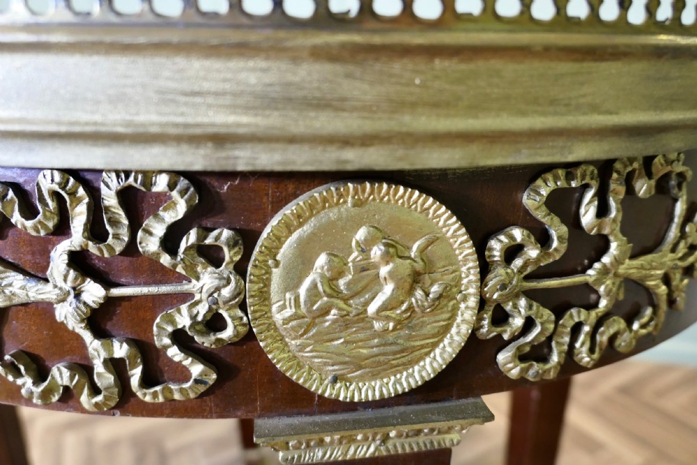 An oval French Empire style mahogany centre table featuring gilt bronze mounts, a brass gallery rim, and tapered legs ending in claw feet. View VI
