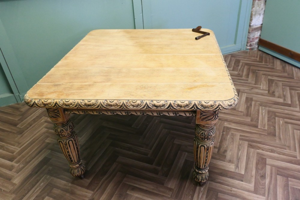 A rectangular bleached oak extending dining table with ornate carved aprons and turned legs. View II