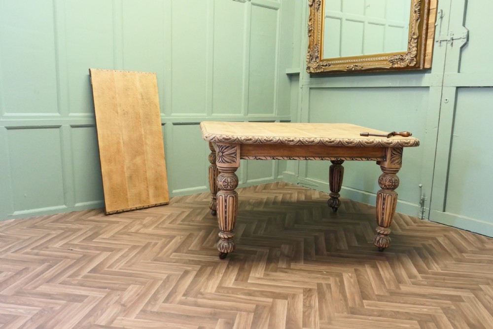 A rectangular bleached oak extending dining table with ornate carved aprons and turned legs. View V