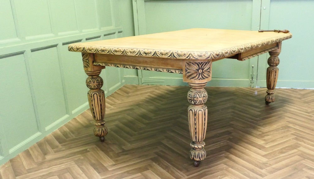 A rectangular bleached oak extending dining table with ornate carved aprons and turned legs. View VI