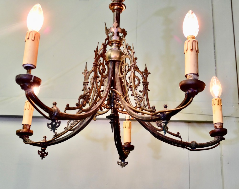 A five-branch gilded brass chandelier featuring Gothic revival openwork tracery, scrolling arms, and candle-style bulb holders. View III