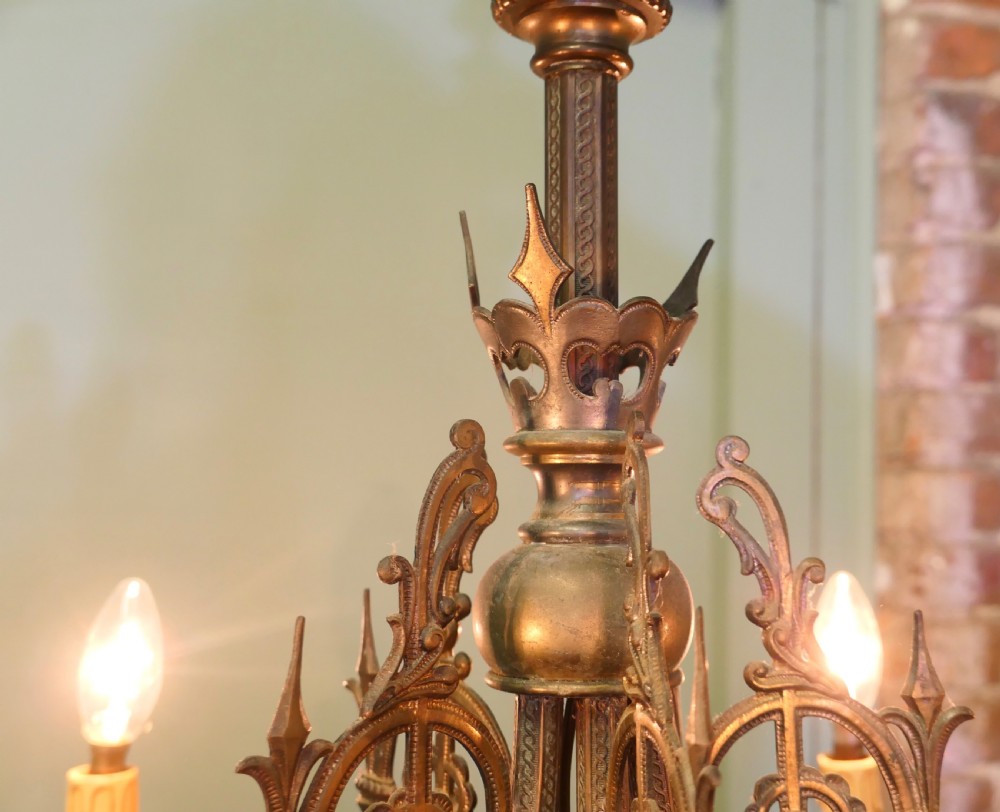 A five-branch gilded brass chandelier featuring Gothic revival openwork tracery, scrolling arms, and candle-style bulb holders. View V