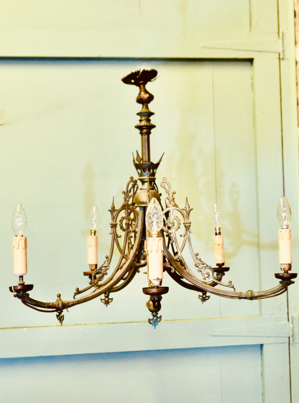 A five-branch gilded brass chandelier featuring Gothic revival openwork tracery, scrolling arms, and candle-style bulb holders. View VI
