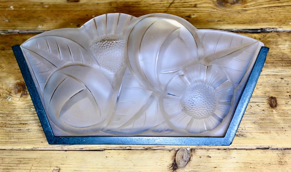 A French Art Deco frosted glass wall light shade featuring press-moulded relief details of stylized flowers and foliage set within a dark metal frame.