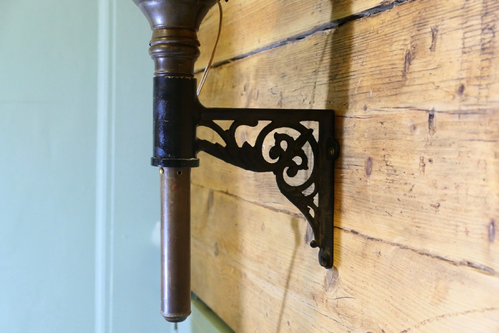 A wall-mounted brass carriage lantern featuring a glazed hexagonal body, decorative pierced collars, a cast eagle finial, and a black wrought scroll bracket. View IV