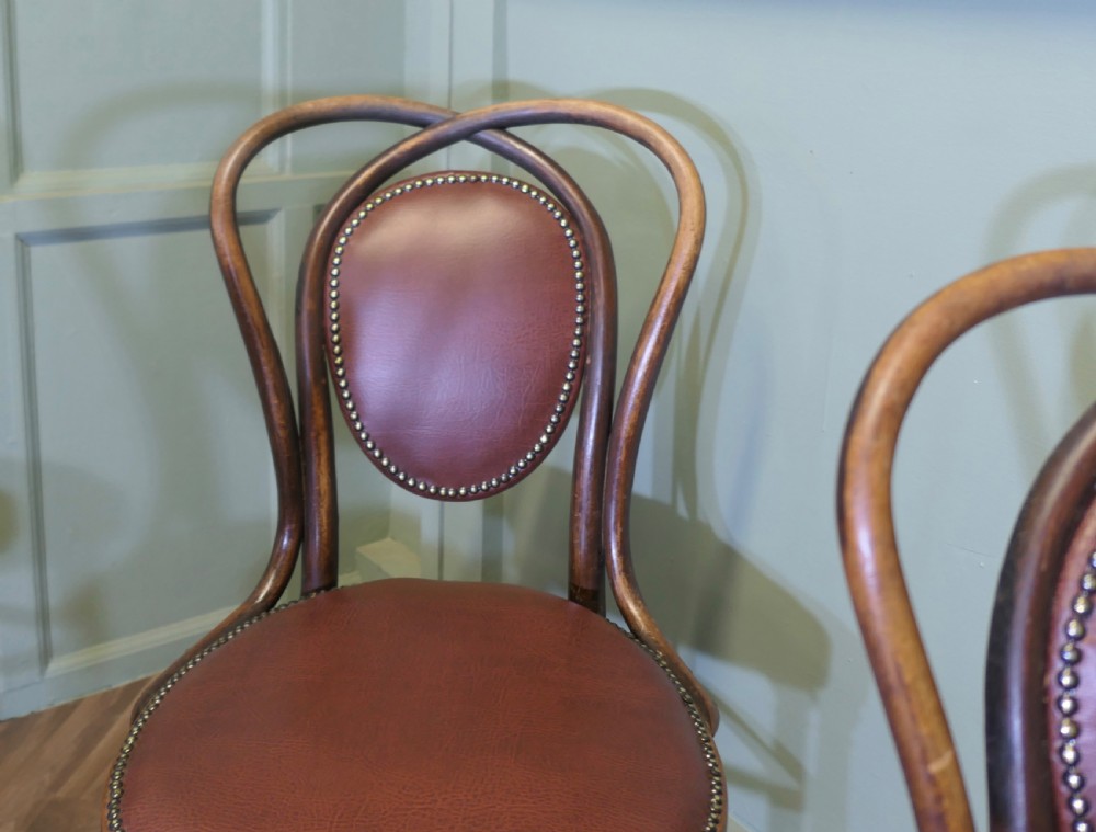 A set of four bentwood bistro dining chairs featuring steam-bent wooden frames and brown leather upholstery detailed with brass studding. View III
