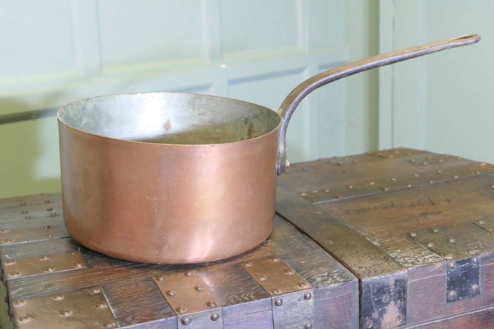 A large 19th-century French copper pot featuring a long iron handle secured with rivets and a tin-lined interior.