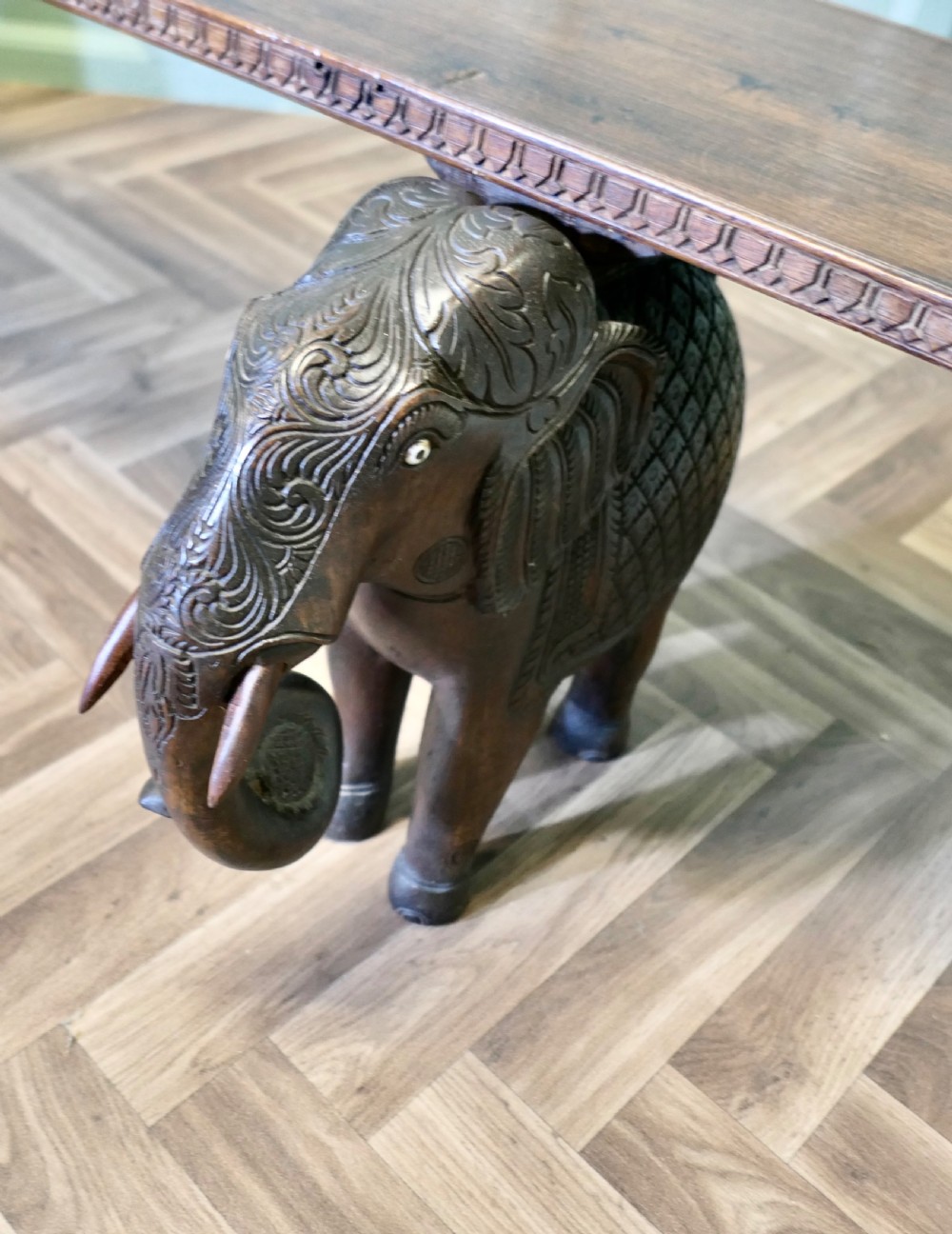 A dark carved wood hall bench featuring a flat rectangular top supported by two detailed elephant figures with raised trunks. View III