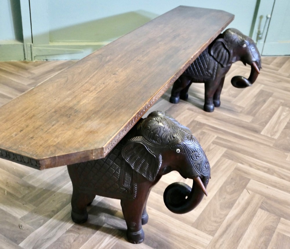 A dark carved wood hall bench featuring a flat rectangular top supported by two detailed elephant figures with raised trunks. View IV