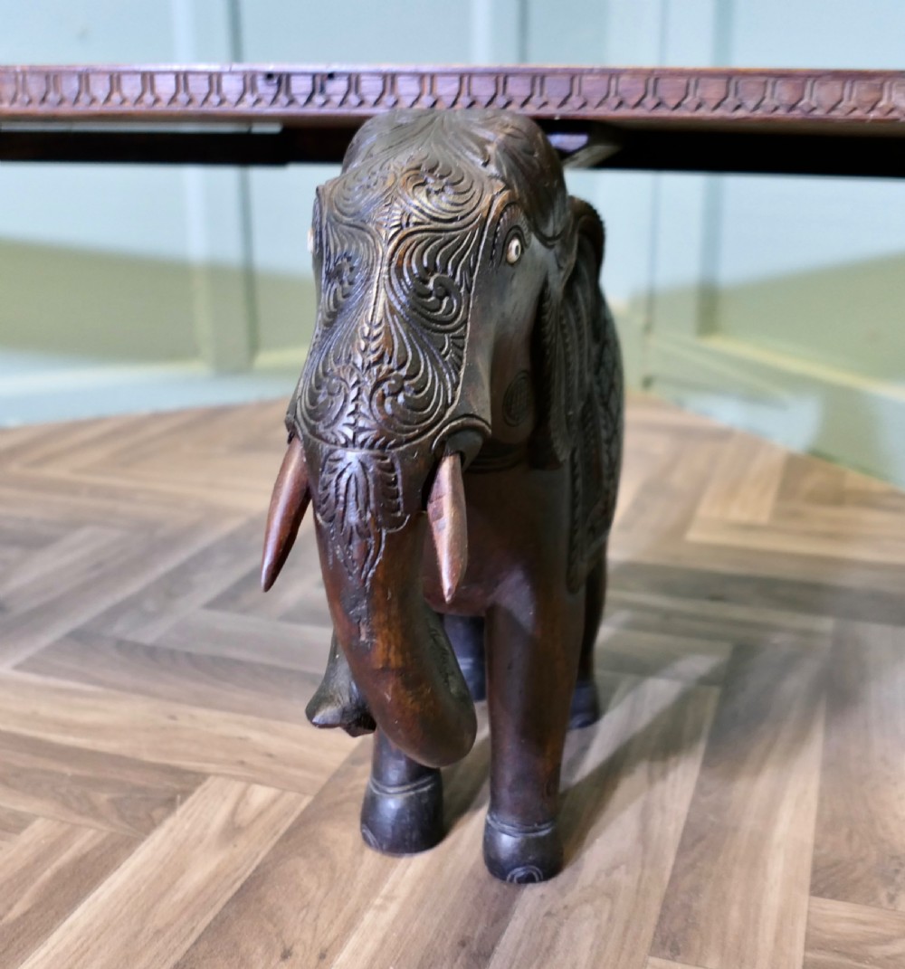 A dark carved wood hall bench featuring a flat rectangular top supported by two detailed elephant figures with raised trunks. View V