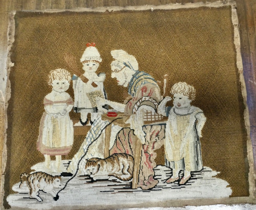 A framed early nineteenth-century wool needlework depicting a classroom scene with a seated teacher, children, and cats. View II