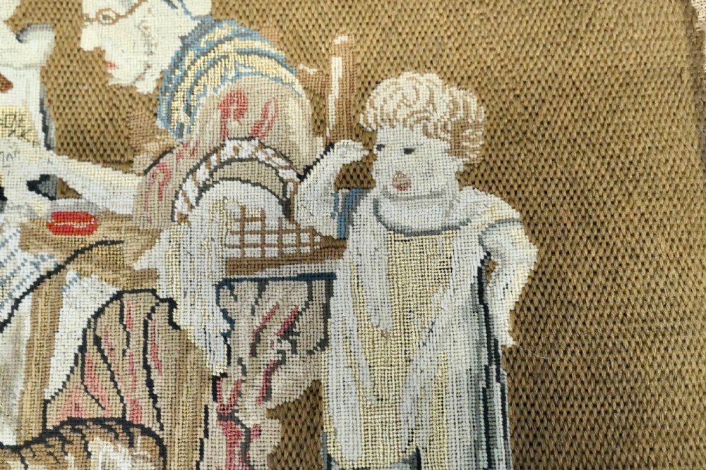 A framed early nineteenth-century wool needlework depicting a classroom scene with a seated teacher, children, and cats. View IV