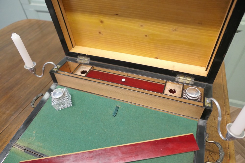 An opened 18th-century satinwood writing slope displaying a green baize writing surface, internal pen tray, glass inkwells, and attached candle sconces. View II
