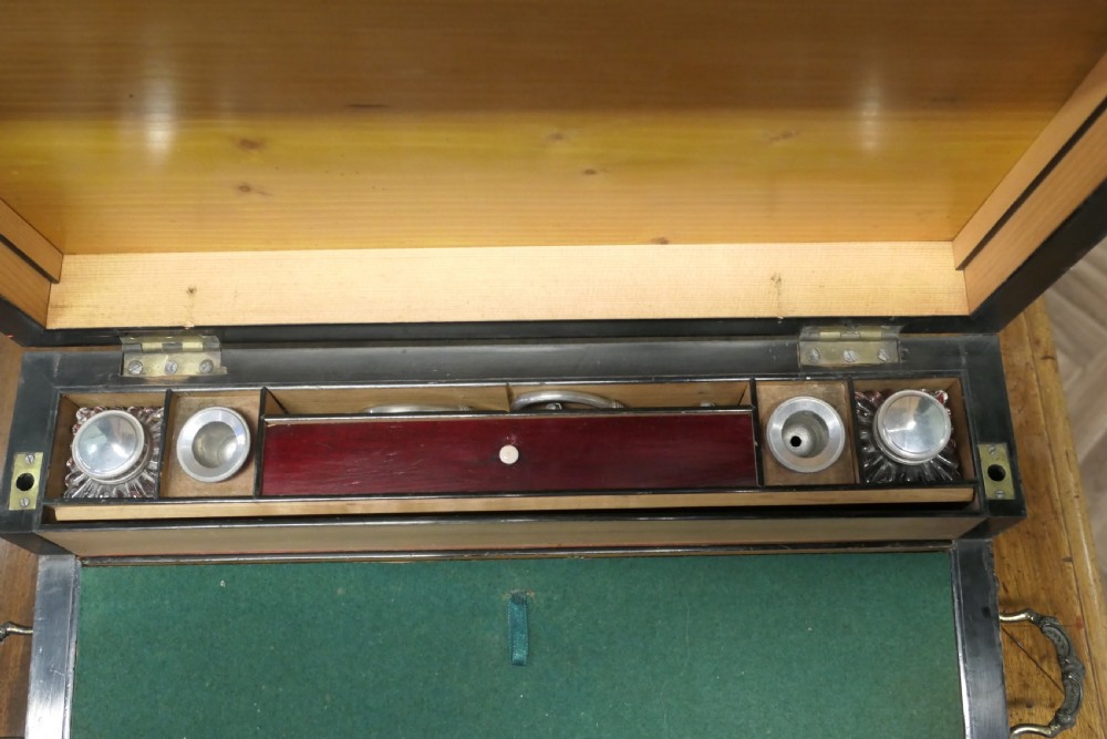 An opened 18th-century satinwood writing slope displaying a green baize writing surface, internal pen tray, glass inkwells, and attached candle sconces. View IV