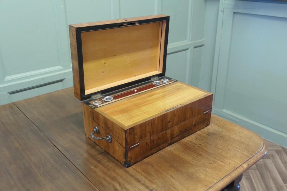 An opened 18th-century satinwood writing slope displaying a green baize writing surface, internal pen tray, glass inkwells, and attached candle sconces. View VIII
