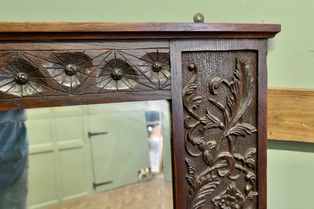 A large rectangular dark oak wall mirror featuring hand-carved foliate side panels, carved urn motifs, a rosette border, and two glass panes. View III